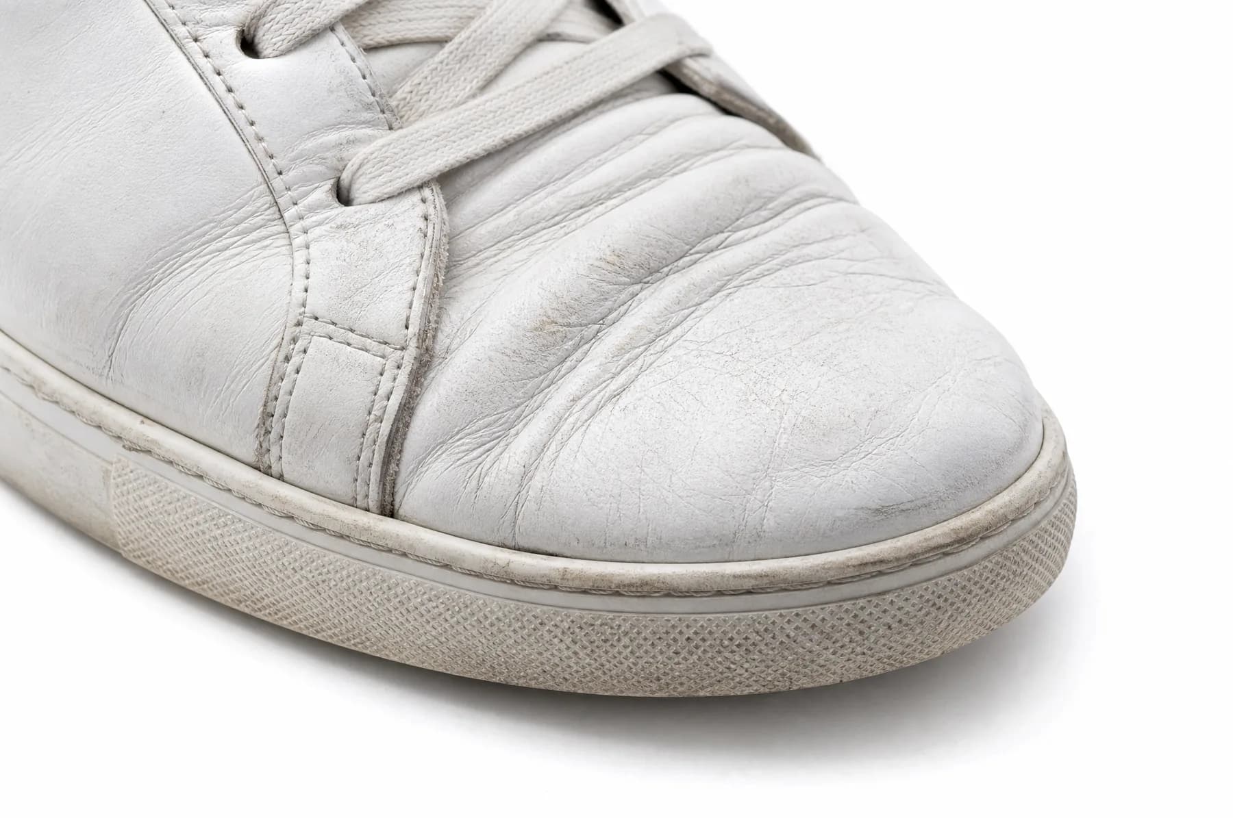 Deep flex creases across the forefoot of a worn white leather shoe